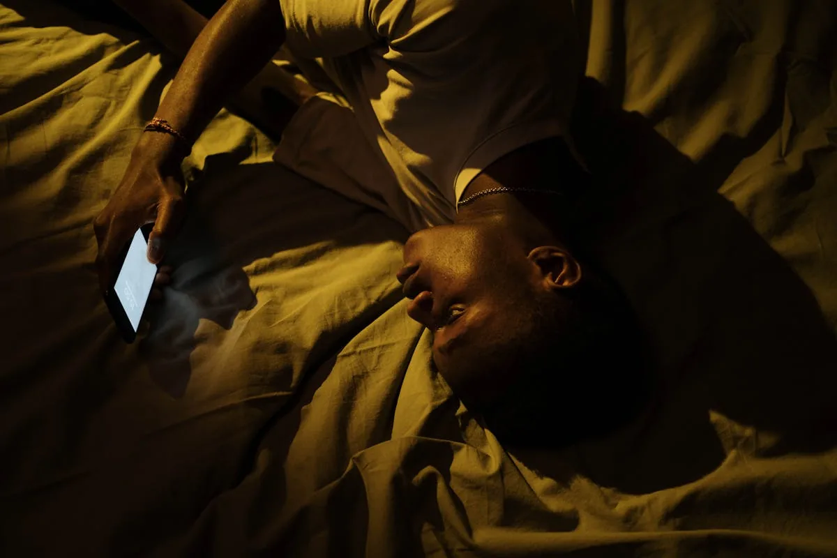 Home mirant el mòbil al llit de nit - les pantalles dificulten agafar el son