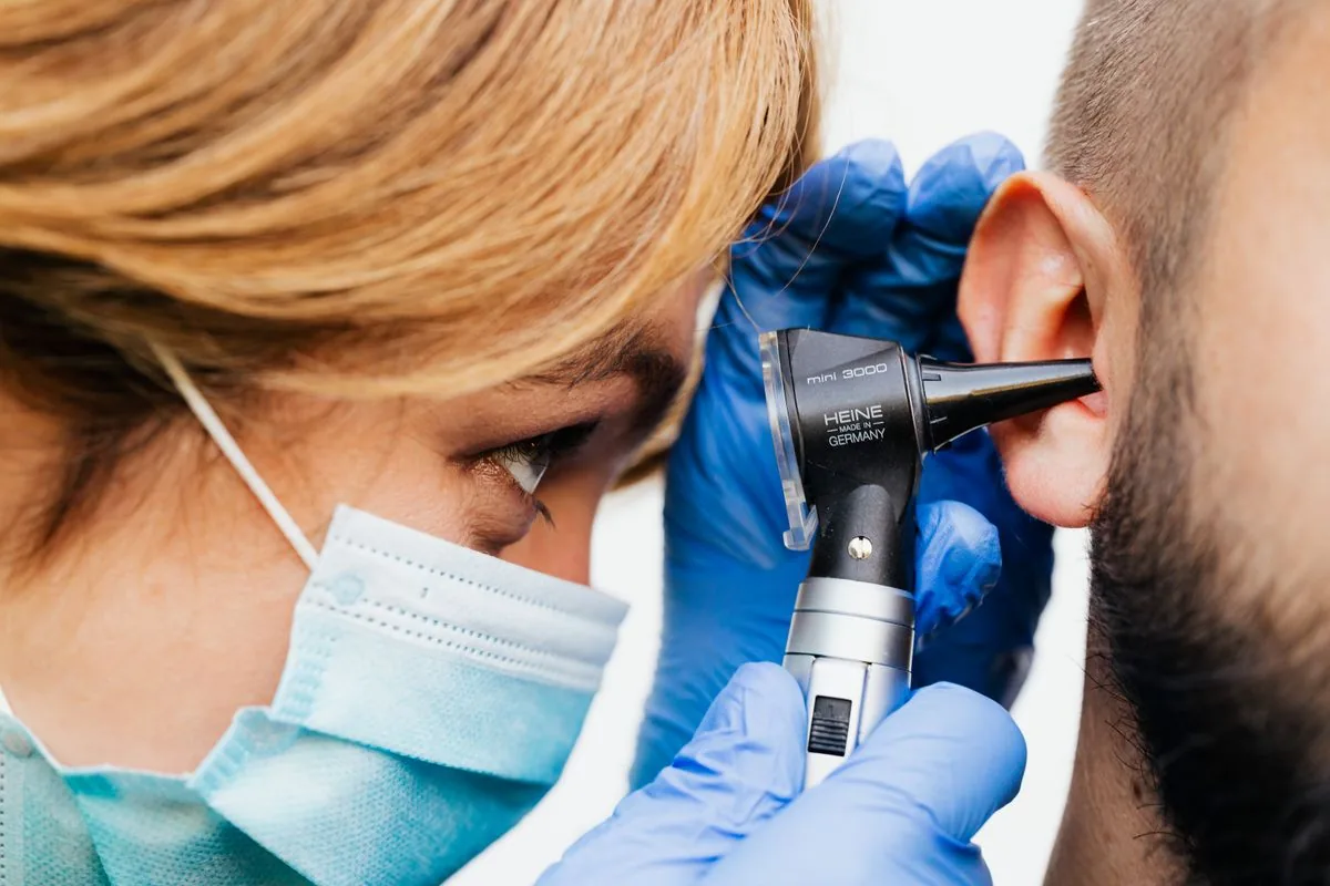 Otorrinolaringòloga explorant l'orella d'un pacient amb un otoscopi per diagnosticar una otitis externa