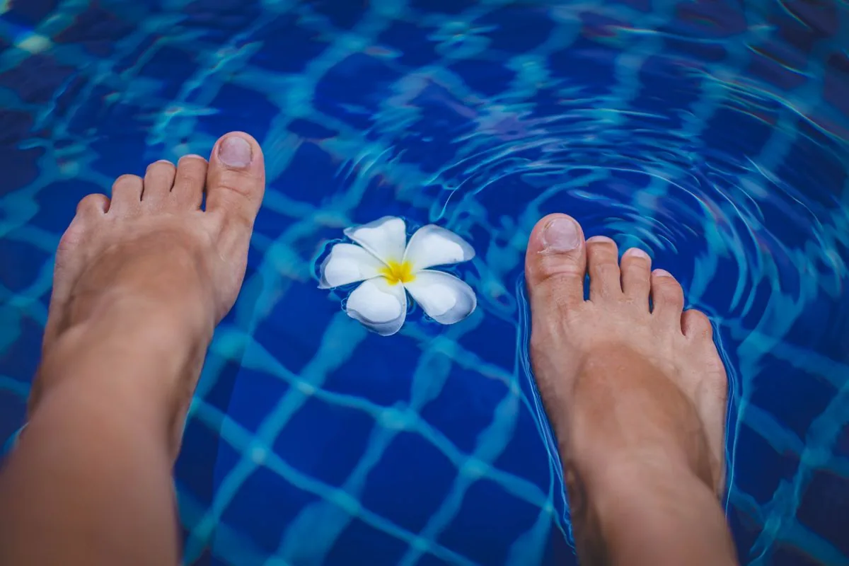 Peus descalços dins l'aigua d'una piscina, situació que afavoreix el contagi del peu d'atleta i els fongs als peus