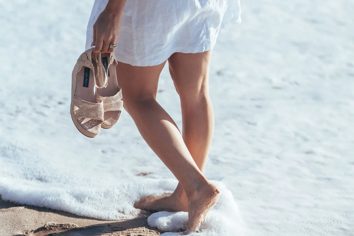 Jambes marchant dans l'écume de la mer sur une plage de la Costa Brava, l'un des gestes les plus simples pour soulager les jambes gonflées en été