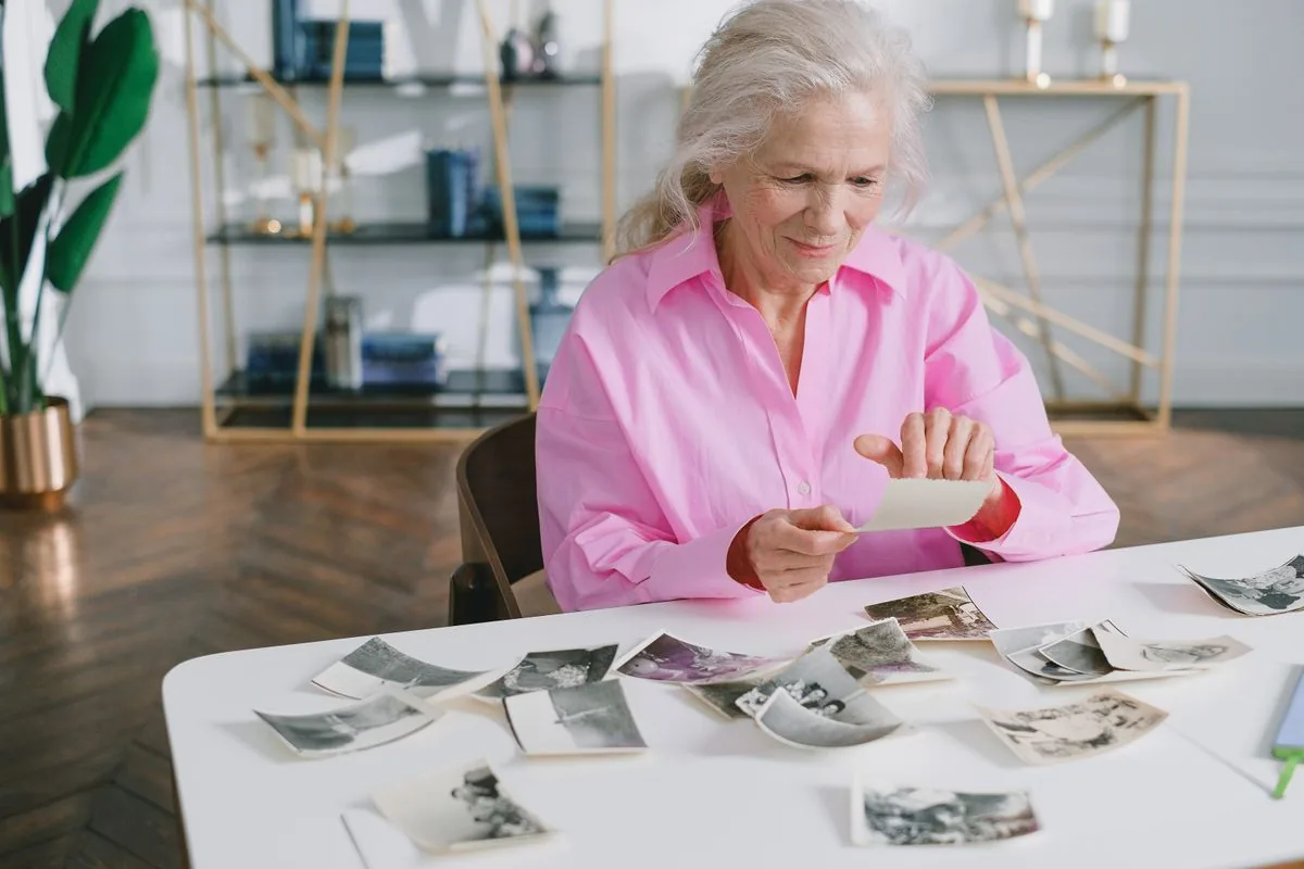 Dona gran repassant fotografies antigues sobre la taula, una escena quotidiana de les queixes de memòria que s'atenen en psicologia geriàtrica