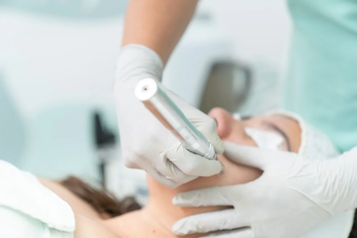 Aplicació d'un aparell de medicina estètica a la línia de la mandíbula d'una pacient, com en un tractament d'HIFU 7D per tensar la pell sense cirurgia