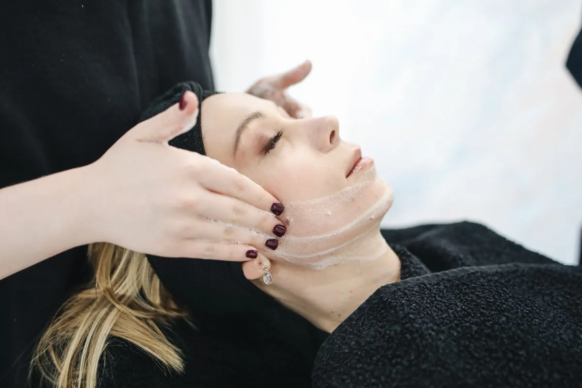 Praticienne réalisant un soin du visage sur une patiente allongée en cabine, comme lors d'une séance de Meso Skin Dual